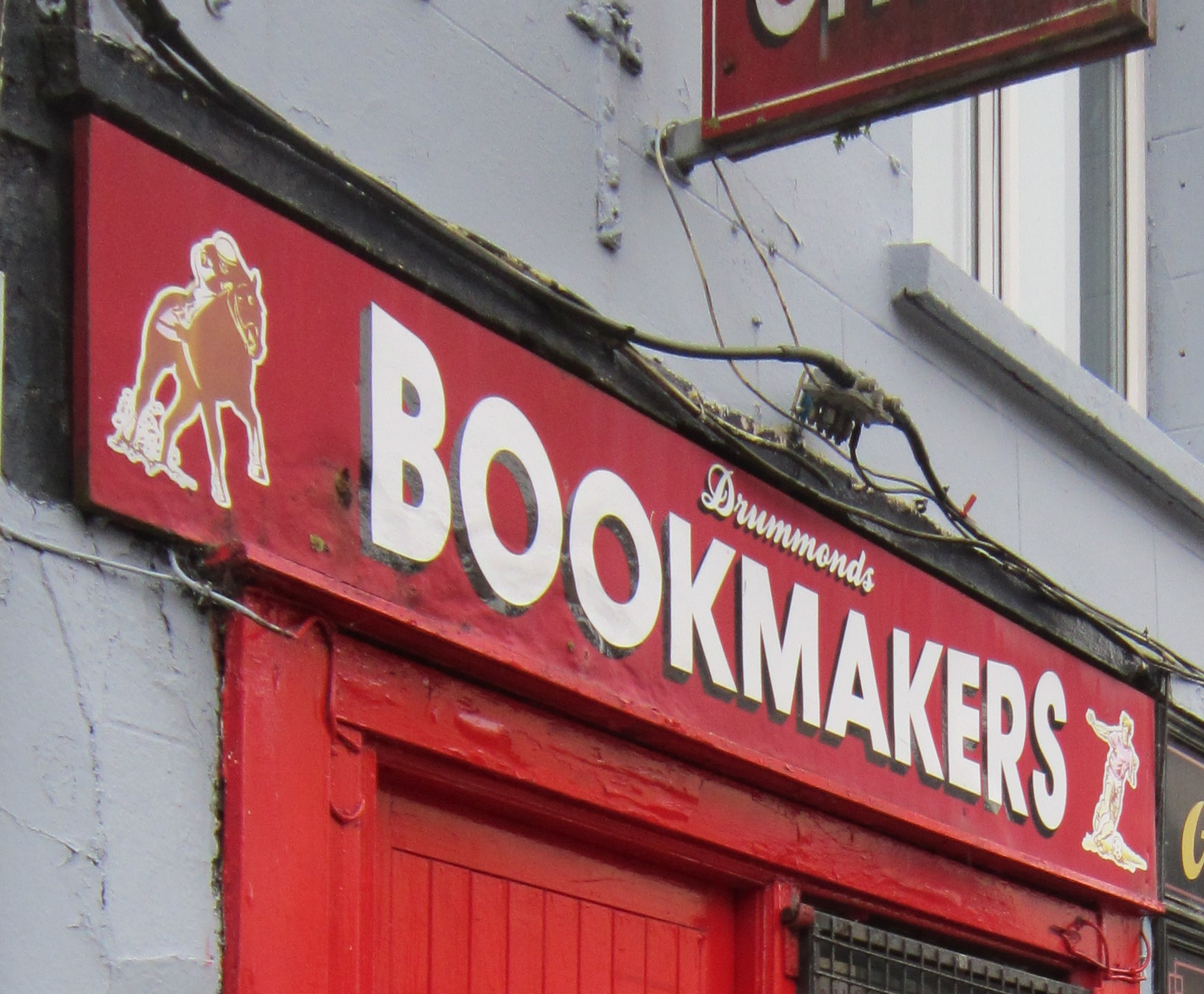 Red sign with image of jockey riding a horse and text that says Drummmonds Bookmakers
